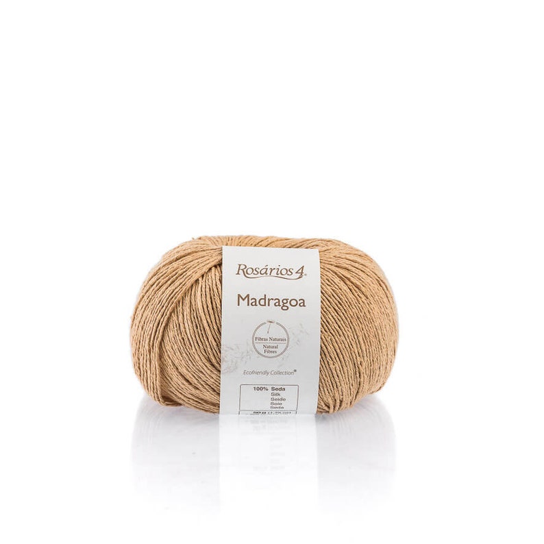 May include: A ball of beige yarn labeled "Ros&aacute;rios 4 Madragoa" with a white label that says "Fibras Naturais Natural Fibers Ecofriendly Collection 100% Seda Silk Seda Soie Seide"