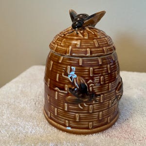 Hand painted ceramic beehive honey jar with spoon. Glossy finish. Raised details. Made in Japan
