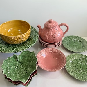 May include: A collection of ceramic tableware in shades of green, yellow, and pink. Includes a teapot, bowls, plates, and leaf-shaped serving dishes. The teapot and some plates have embossed designs.