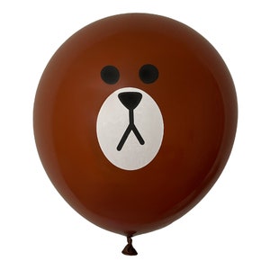 Pu&ograve; includere: Un palloncino marrone con una faccia bianca e occhi, naso e bocca neri. La faccia assomiglia a un orso dei cartoni animati.