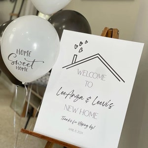 May include: A white sign with black text and a simple house drawing welcomes Lee Anza & Leevi's to their new home. The sign also includes the date 6 April 2024 and the phrase "Thanks for stopping by!"