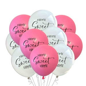 May include: A bunch of pink and white balloons with the text "Home Sweet Home" written on them.