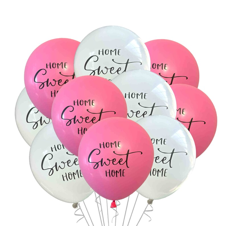 May include: A bunch of pink and white balloons with the text "Home Sweet Home" written on them.