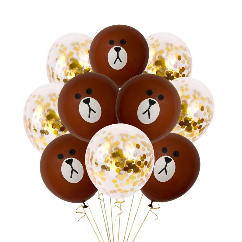 Pu&ograve; includere: Un mazzo di palloncini marroni con un viso di orso disegnato su di essi. I palloncini sono legati insieme con uno spago dorato. Alcuni dei palloncini sono trasparenti con coriandoli dorati all'interno.