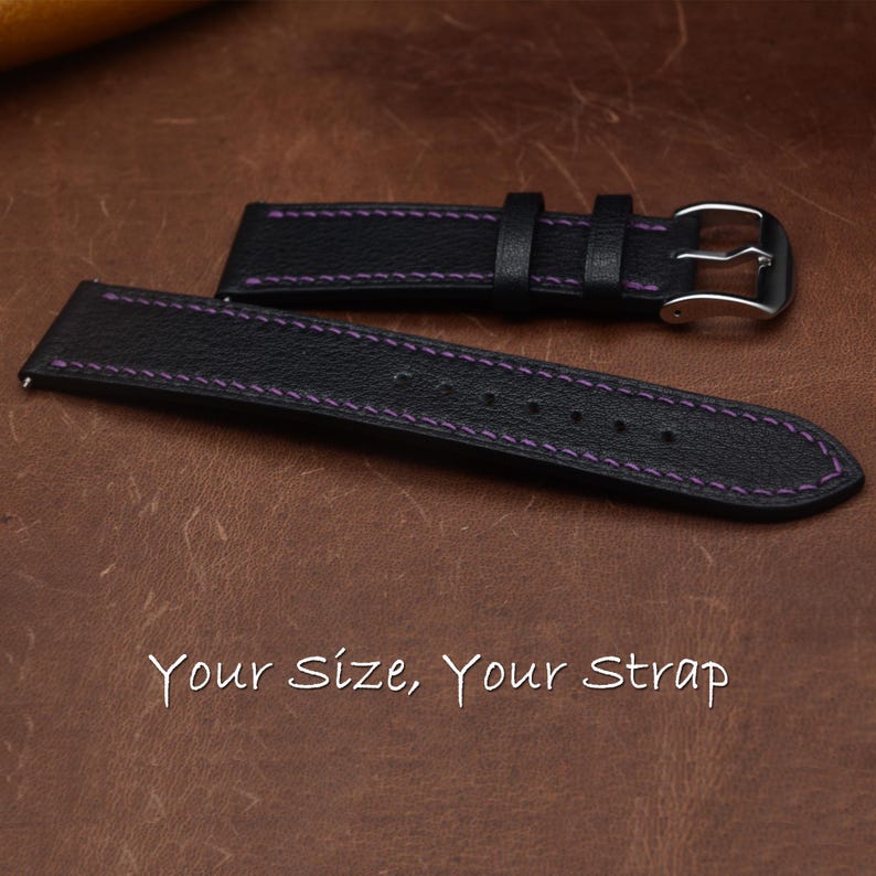 May include: A black watch strap with a textured surface and purple stitching. The strap features a silver-toned metal buckle and two loops. The text "Your Size, Your Strap" is printed in white at the bottom of the image.