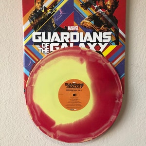 May include: A vinyl record from the Guardians of the Galaxy Awesome Mix Vol. 1 soundtrack. The record is yellow and red, with the album title and tracklist visible. The album cover features characters from the movie.