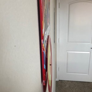 May include: A red and yellow vinyl record mounted on a wall, with a red rectangular album cover behind it. The album cover has text and images, and the record is circular with a yellow center.