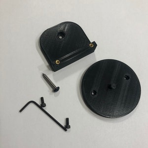 May include: Black 3D-printed components, including a curved bracket with brass inserts, a circular base, a screw, and an Allen wrench. The parts are arranged on a white surface, suggesting a DIY or repair kit.