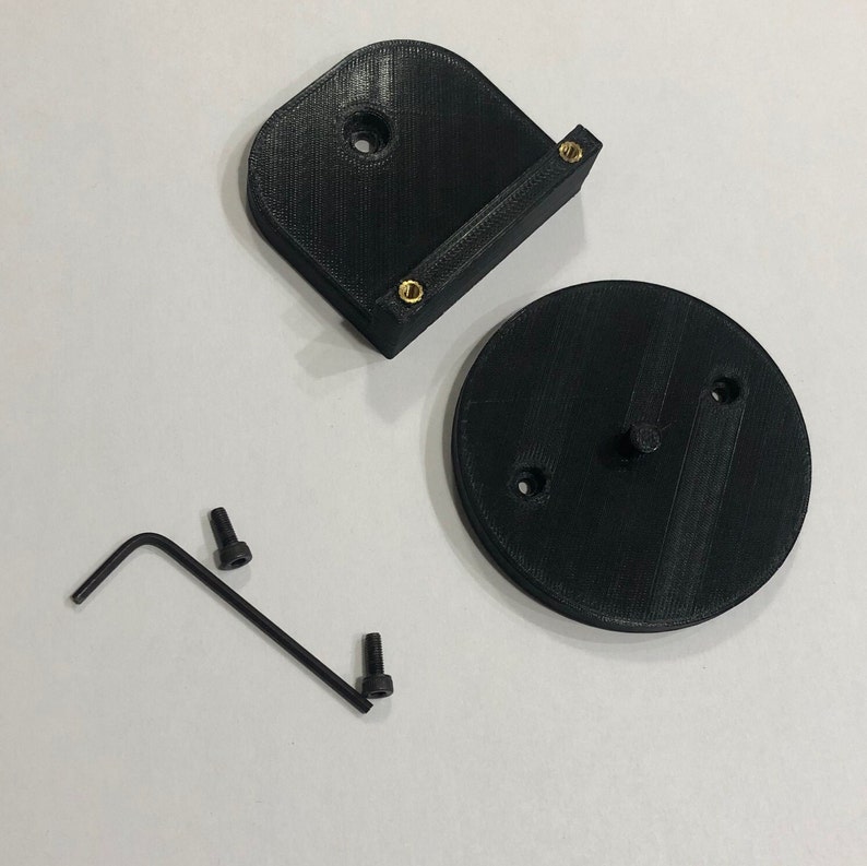 May include: Black 3D-printed parts, including a curved bracket with brass inserts, a circular base, two screws, and an Allen wrench. The parts are arranged on a white surface, suggesting a DIY or repair kit.
