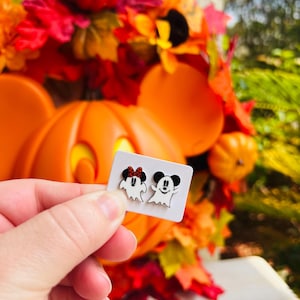 May include: A white ceramic mug with a black handle and the text "But First, Coffee" in a bold, black font. The mug is set against a blurred background, suggesting a cozy setting.