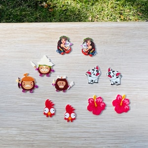 May include: A set of 10 colorful cartoon character earrings. The earrings feature a variety of characters, including a pig, a rooster, a monkey, a hibiscus flower, and a woman with a pig. The earrings are made of wood and are painted in bright colors.