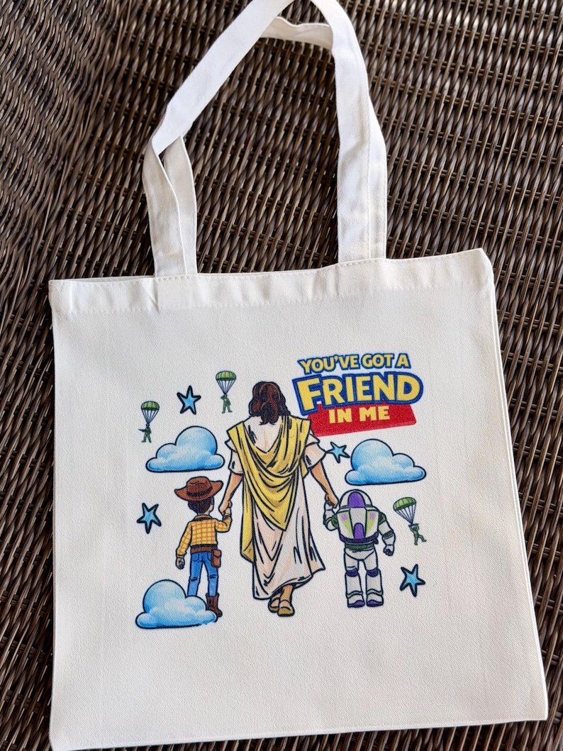 Pu&ograve; includere: Borsa tote in tela color crema con manici bianchi. La borsa presenta una grafica colorata di Ges&ugrave; che tiene per mano Woody e Buzz Lightyear, con la scritta "YOU'VE GOT A FRIEND IN ME". Nuvole blu, stelle e paracadute completano il design.