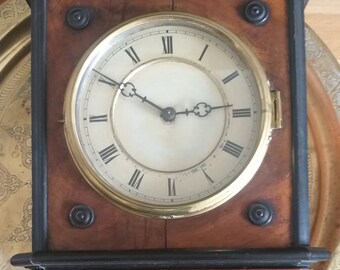 Antiguo reloj de pared con péndulo de madera y latón.