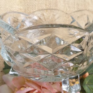 Op de afbeelding: Een glazen kom met een diamantpatroon en drie poten. De kom staat op een jute achtergrond.