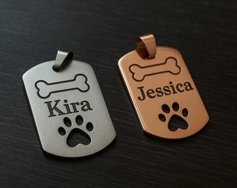 May include: Two rectangular metal pet ID tags with rounded corners and a top bail. One tag is silver-toned with the engraved name Kira, a bone icon, and a cutout paw print. The other tag is rose gold-toned with the engraved name Jessica, a bone icon, and a cutout paw print.
