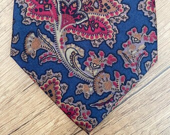 Könnte beinhalten: Eine blaue Seidenkrawatte mit einem Paisley-Muster in Braun-, Rot- und Cremetönen.