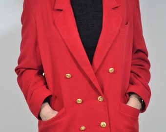Könnte beinhalten: Ein roter zweireihiger Blazer mit goldenen Knöpfen. Der Blazer hat zwei Taschen auf der Vorderseite und ist aus einem weichen, warmen Stoff gefertigt.