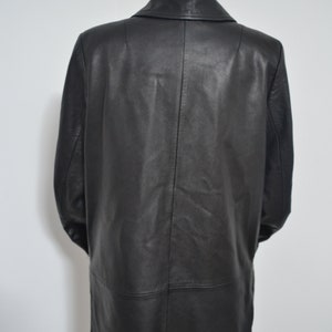 May include: A long black leather coat with a collar and a single button closure. The coat is on a mannequin.
