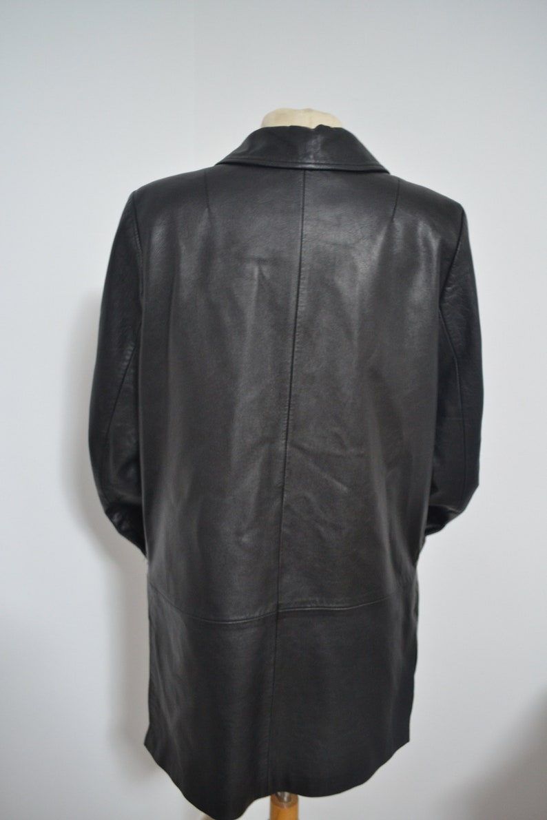 May include: A long black leather coat with a collar and a single button closure. The coat is on a mannequin.