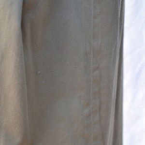 May include: Close-up of a khaki-colored fabric with a seam running down the side. The fabric has a subtle texture and a slight sheen.