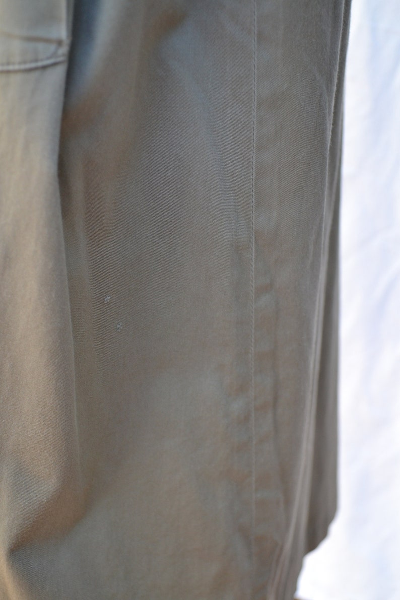 May include: Close-up of a khaki-colored fabric with a seam running down the side. The fabric has a subtle texture and a slight sheen.