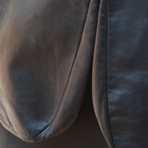 May include: Close-up of a black leather jacket with a seam down the center of the back.