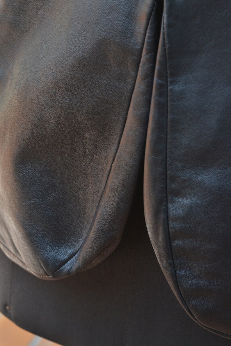May include: Close-up of a black leather jacket with a seam down the center of the back.