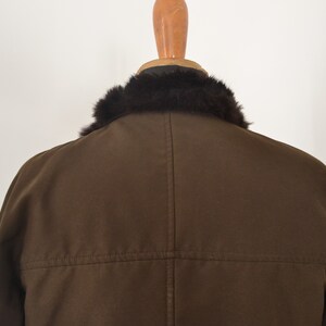 K&ouml;nnte beinhalten: Eine braune Jacke mit einem schwarzen Pelzkragen. Die Jacke hat einen Rei&szlig;verschluss und eine Naht auf der R&uuml;ckseite.