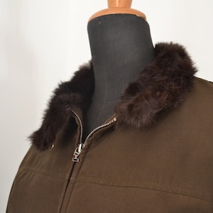 K&ouml;nnte beinhalten: Eine braune Jacke mit einem Pelzkragen. Die Jacke hat einen Rei&szlig;verschluss und ein braunes Futter.