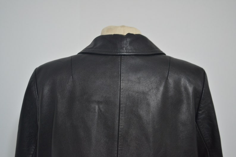 May include: Black leather jacket with a classic collar and a single-breasted closure. The jacket has a smooth, polished finish.