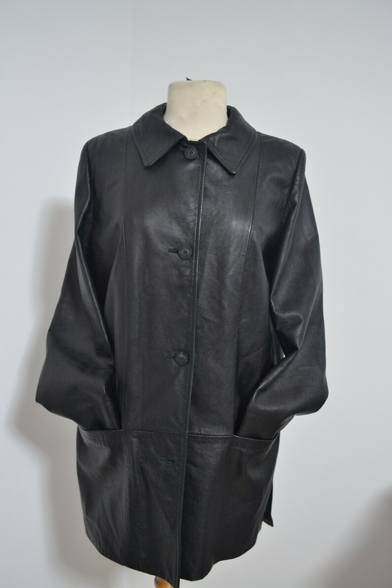 May include: A black leather jacket with a button-up front and two pockets. The jacket has a collar and long sleeves.