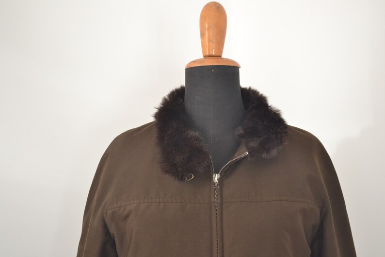 K&ouml;nnte beinhalten: Eine braune Jacke mit Rei&szlig;verschluss und einem braunen Pelzkragen.