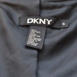 May include: A black leather jacket with a DKNY label and a size 6 tag. The label lists the material as 100% leather and the lining as 100% polyester. The jacket was made in China.