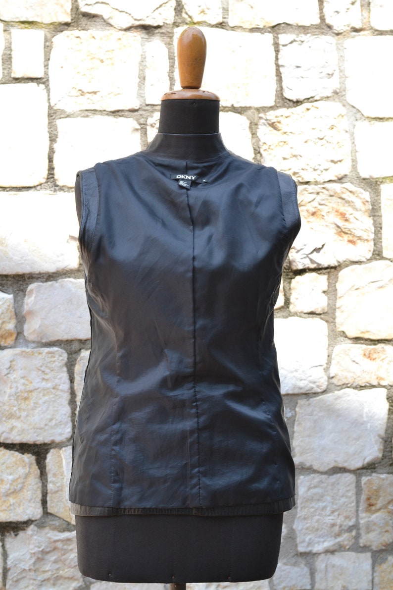 May include: Black sleeveless jacket with a zipper closure and a DKNY label on the back.