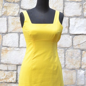May include: A sleeveless yellow dress with a square neckline and a fitted silhouette.