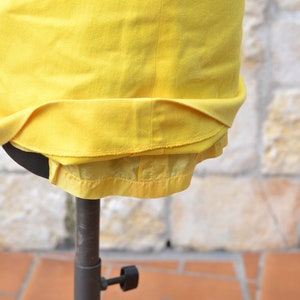 May include: A yellow skirt with a zipper closure and a satin lining. The skirt is displayed on a mannequin.