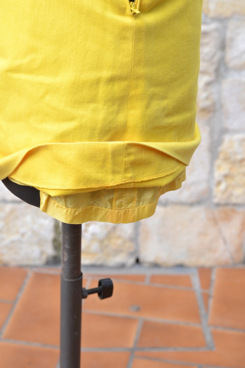 May include: A yellow skirt with a zipper closure and a satin lining. The skirt is displayed on a mannequin.