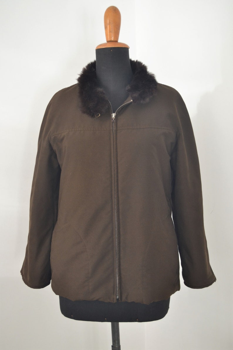 K&ouml;nnte beinhalten: Eine braune Rei&szlig;verschlussjacke mit einem Kunstfellkragen. Die Jacke hat einen Rei&szlig;verschluss und ein gestepptes Futter.