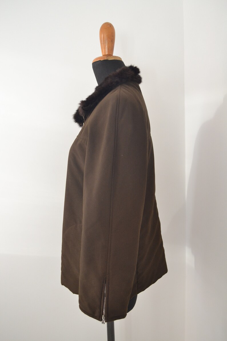 K&ouml;nnte beinhalten: Eine braune Jacke mit einem Pelzkragen. Die Jacke hat einen Rei&szlig;verschluss an der Seite.