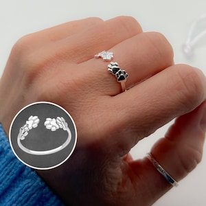 Op de afbeelding: Zilveren ring met een ontwerp van drie poot afdrukken. De ring is open en verstelbaar.