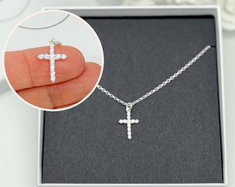 May include: A silver necklace with a small, sparkling cross pendant. The cross is set with clear cubic zirconia stones.