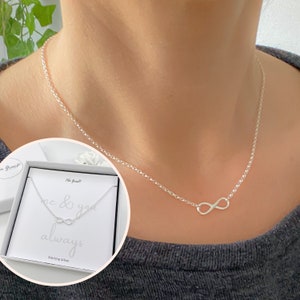 May include: A silver infinity necklace with a delicate chain. The necklace comes in a small white box with the text "me & you always" and "sterling silver".