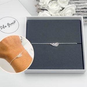 May include: A silver bracelet with a delicate wing charm. The bracelet is displayed in a black velvet box with the brand name "Lila Grace Jewelry" on the lid.