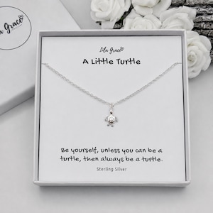 May include: A silver-toned necklace with a small turtle pendant, presented in a white gift box. The box features the text Lila Grace, A Little Turtle, and the quote: Be yourself, unless you can be a turtle, then always be a turtle. Sterling Silver.