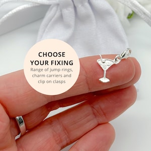 May include: A silver martini glass charm with a clip fastening. The charm is held up against a white background. A circular label displays the text "CHOOSE YOUR FIXING" and details jump rings, charm carriers, and clip-on clasps.