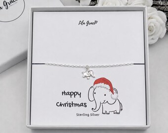 May include: A sterling silver chain bracelet with an elephant charm, presented in a white gift box. The display card features a cartoon elephant wearing a red Santa hat, the text "Happy Christmas" and "Sterling Silver", and the Lila Grace logo.