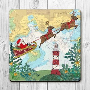 May include: Square coaster with a festive Christmas design. Santa Claus in a sleigh, pulled by reindeer, flies over a nautical chart. A lighthouse and evergreen trees are also shown. The coaster has a map background.
