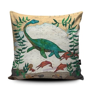 May include: A decorative cushion featuring a green and blue dinosaur swimming in a sea of red fish. The background is a vintage nautical map with the words "England" and "Lime Bay".