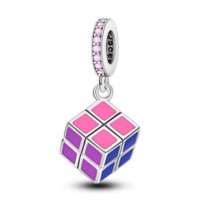 May include: A silver charm with a pink and purple enamel Rubik's Cube design. The charm has a small loop at the top for attaching to a bracelet or necklace.