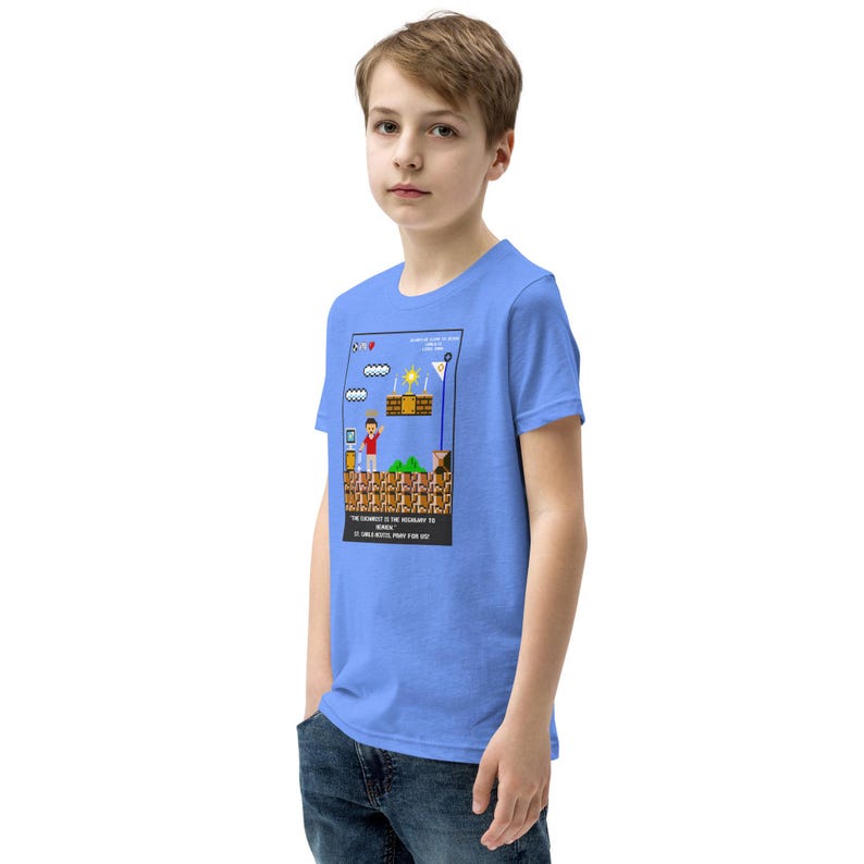 May include: A light blue t-shirt for kids featuring a pixelated image of a video game character standing on a platform. The text on the shirt reads "THE STRUGGLE IS THE NECESSARY TO REACH HEAVEN. 12 CHALLENGES, PRAY FOR HIM."